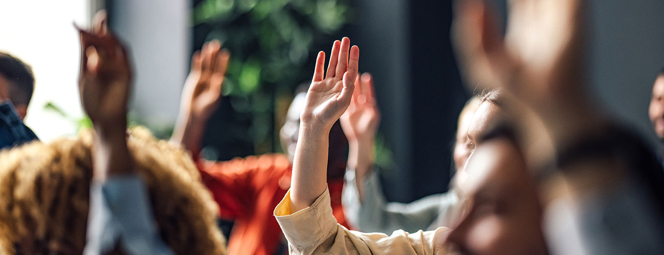 A group of people with their hands up to ask a question