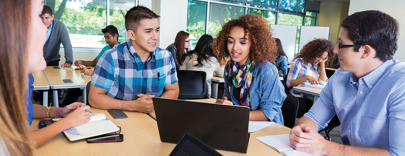 Four students gathered around a table talking