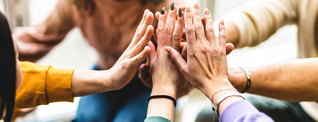 A team putting their hands in a circle during a meeting