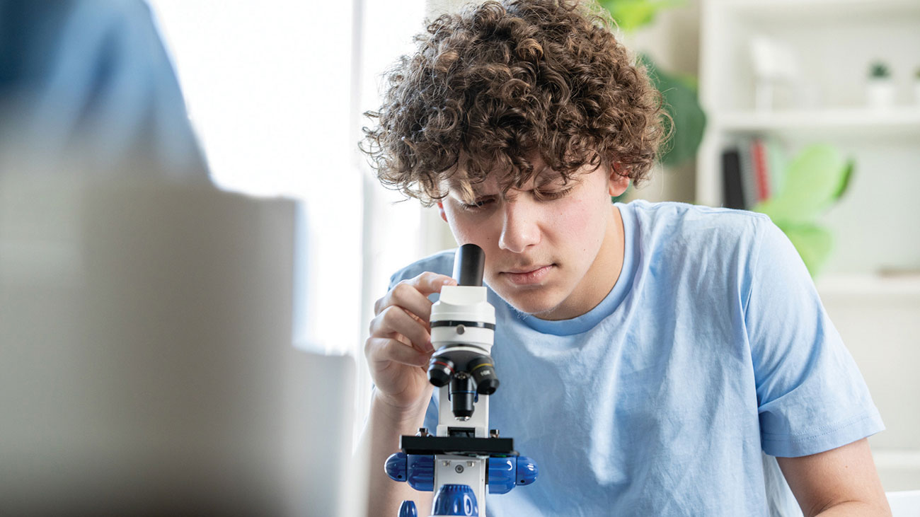 A student looking through a microscope in the medicine and health care strand