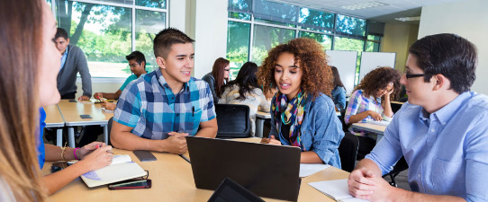 Four students gathered around a table talking